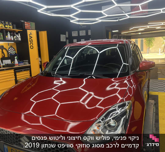 מכונית אדומה בחדר דיטיילינג עם תאורה חזקה